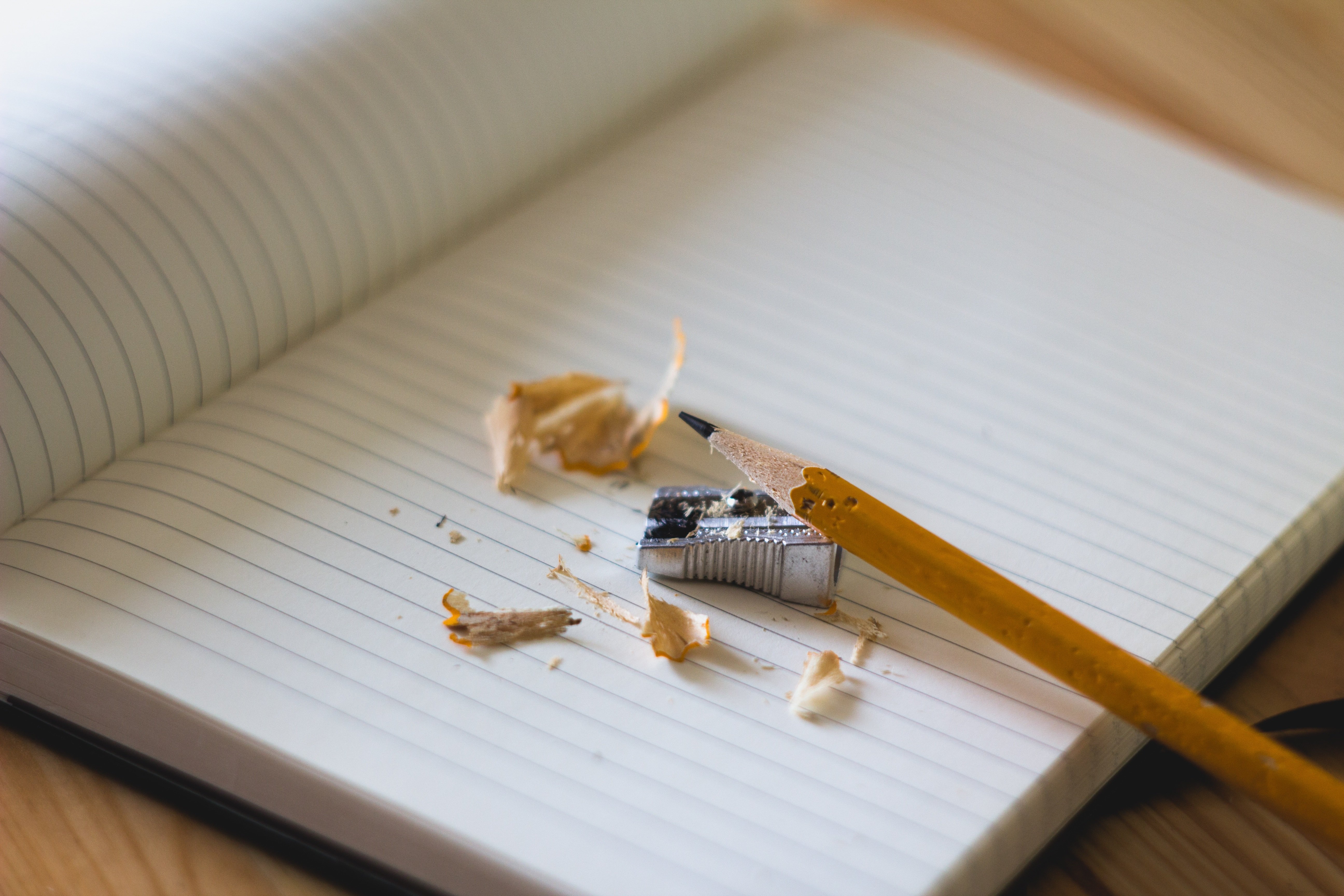 A pencil and a pencil sharpener lying on a notebook.